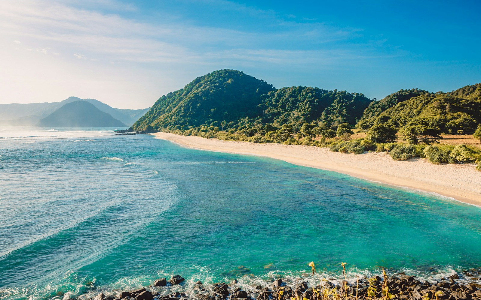 Sandy beach and lush hills along the coastline of Fiji islands.