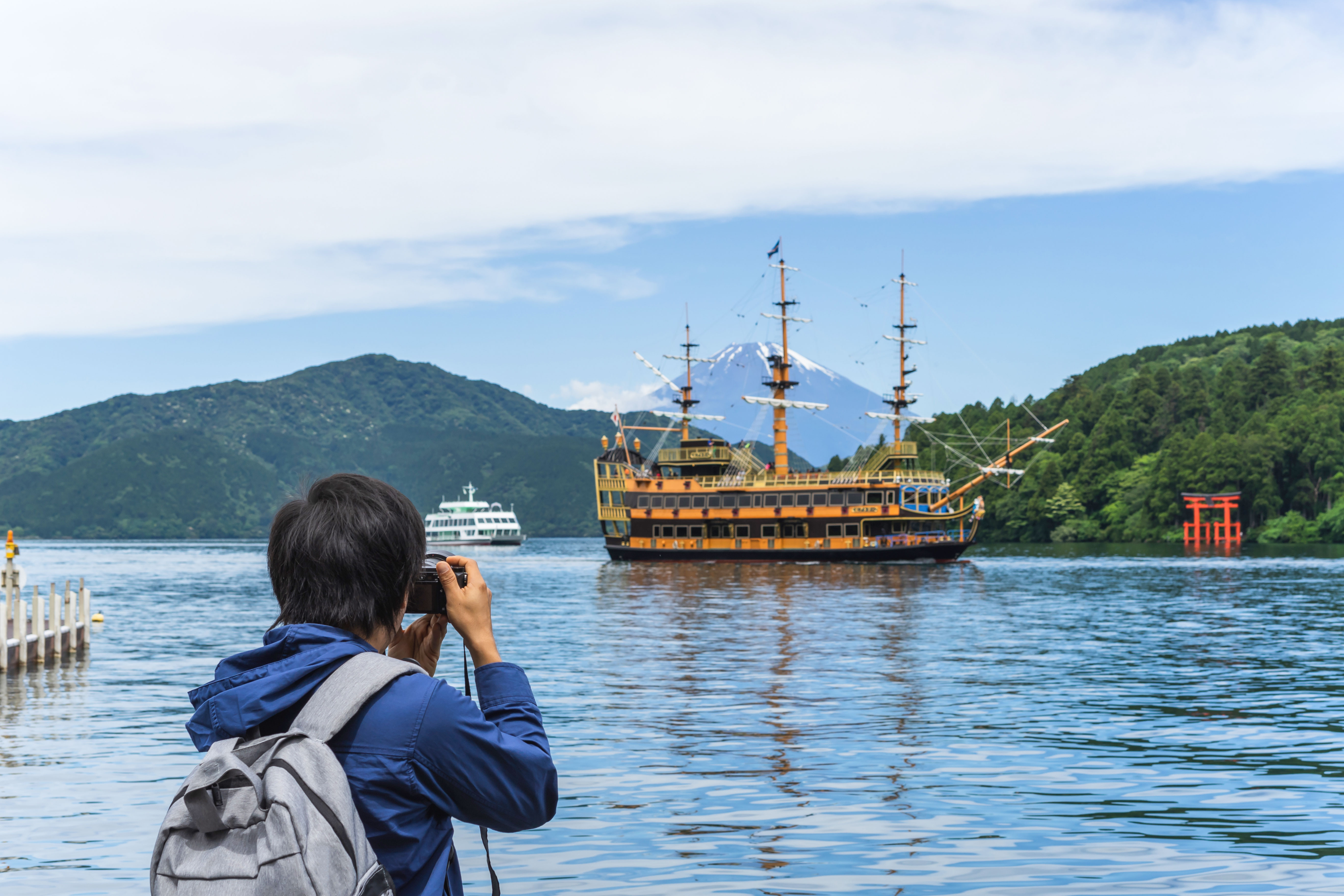 Young traveler photographing pirate ship on Lake Ashi near Hakone Shrine, Japan.