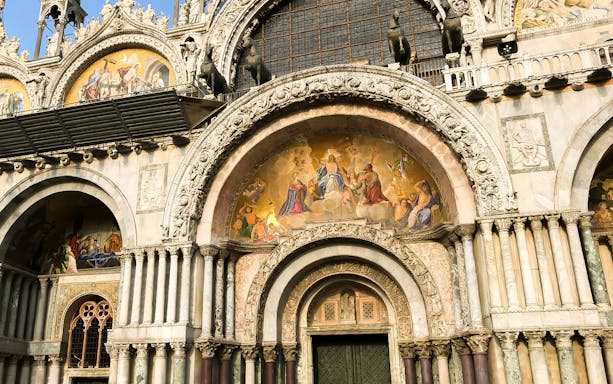 Facade of St. Mark's Basilica in Venice with detailed mosaics and sculptures.