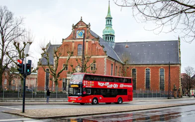 Red Sightseeing's Copenhagen hop-on hop-off bus near historic church.