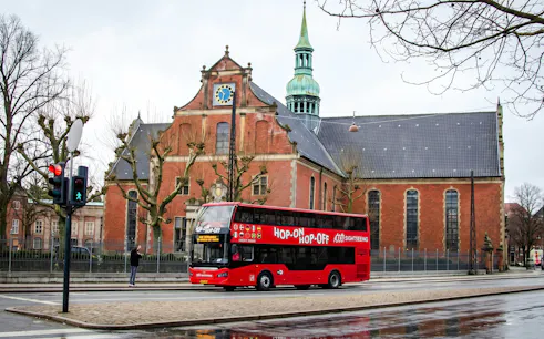 Red Sightseeing's Copenhagen hop-on hop-off bus near historic church.