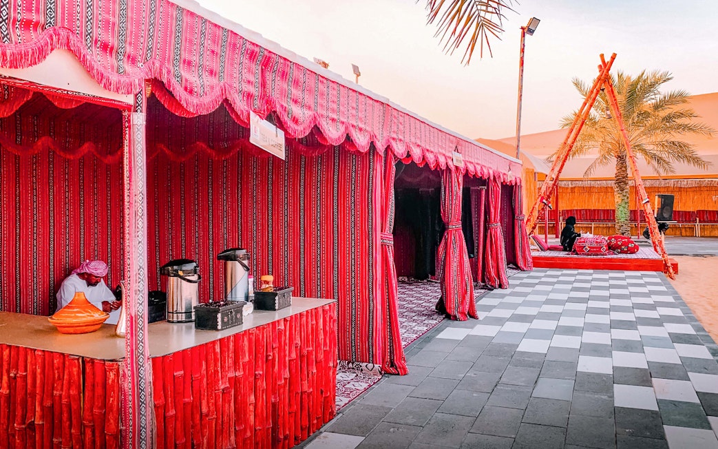 Desert camp setup with red tents and seating area in Abu Dhabi for evening safari.