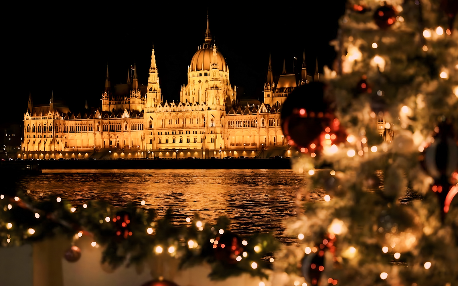 Hungarian Parliament lit at night with Christmas decorations on a river cruise, Budapest.