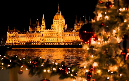 Hungarian Parliament lit at night with Christmas decorations on a river cruise, Budapest.