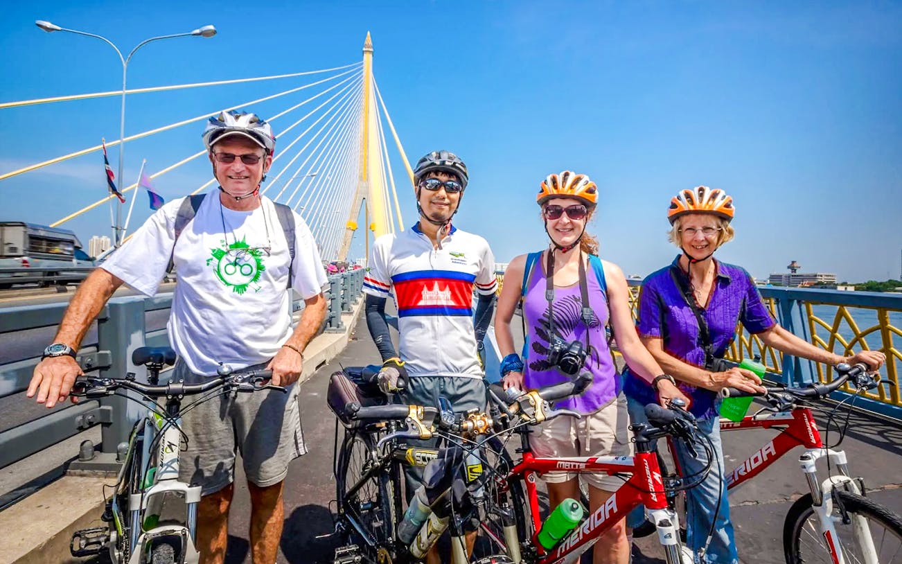 Guide and tourists on bicycles at Rama bridge, Bangkok cycling tour.
