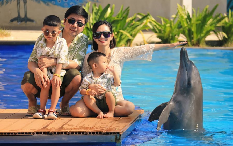 Family interacting with a dolphin at a poolside attraction.