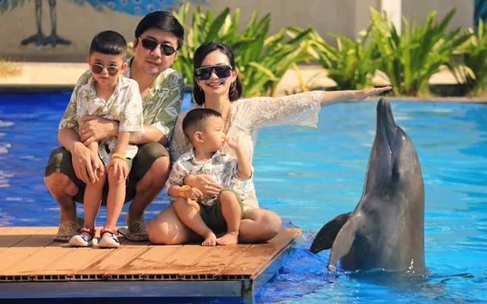 Family interacting with a dolphin at a poolside attraction.