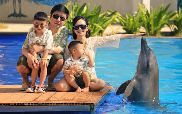 Family interacting with a dolphin at a poolside attraction.