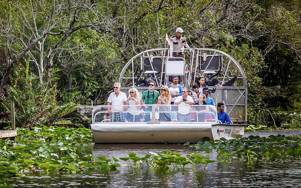 Airboat tour in Everglades Safari Park with group observing wildlife, Miami transfer included.