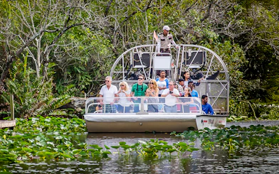 Airboat tour in Everglades Safari Park with group observing wildlife, Miami transfer included.