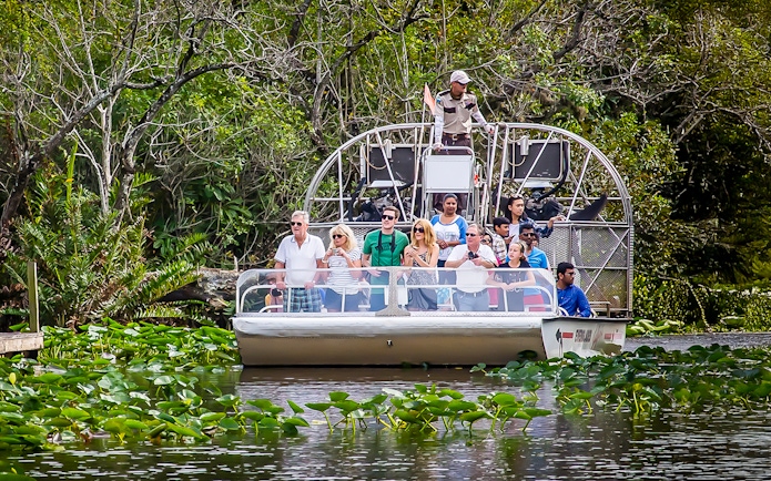 Airboat tour in Everglades Safari Park with group observing wildlife, Miami transfer included.