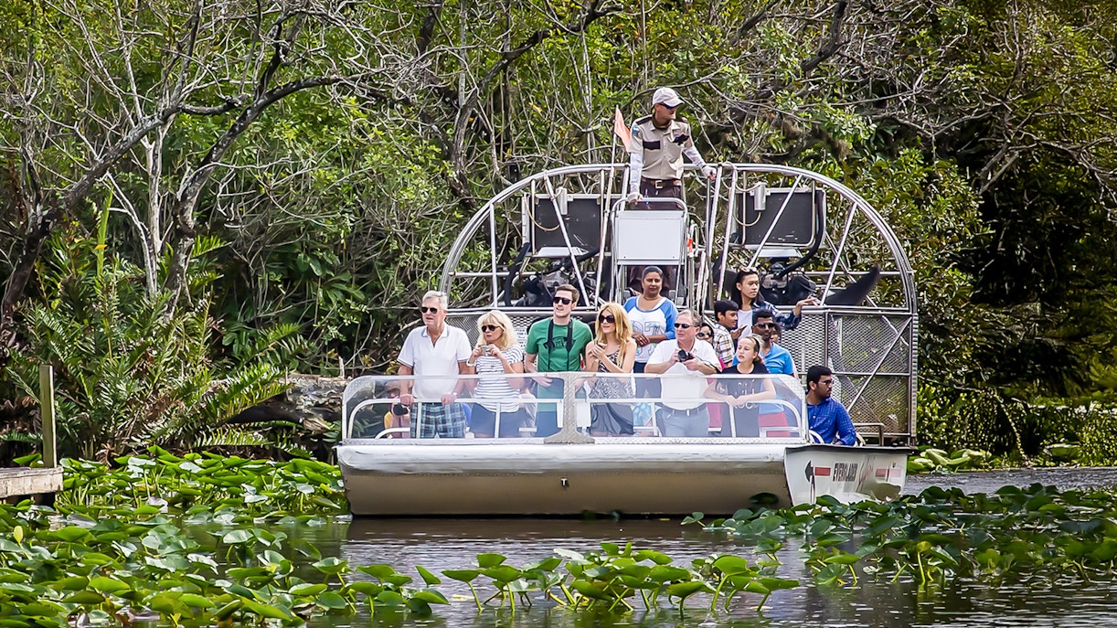 Airboat tour in Everglades Safari Park with group observing wildlife, Miami transfer included.