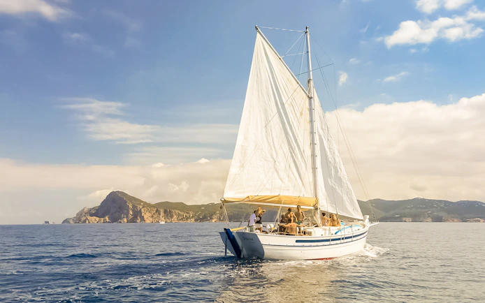Tourists on a classic sailboat during a private sunset cruise near Ibiza's coastline.