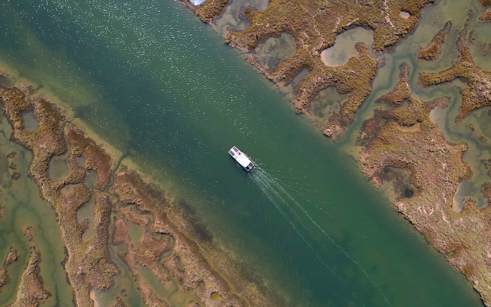 Aerial view of a boat navigating through the Ria Formosa lagoon in Algarve, Portugal.
