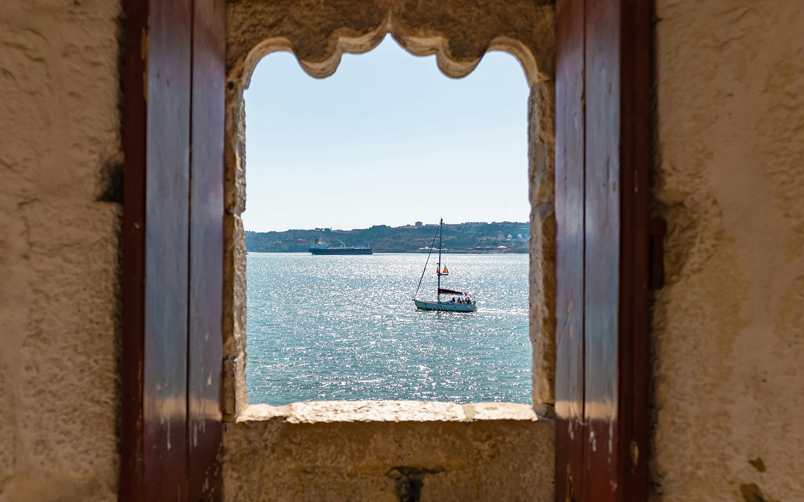 View of a sailboat on the Tagus River from Belem Tower's King's Chamber, Lisbon.