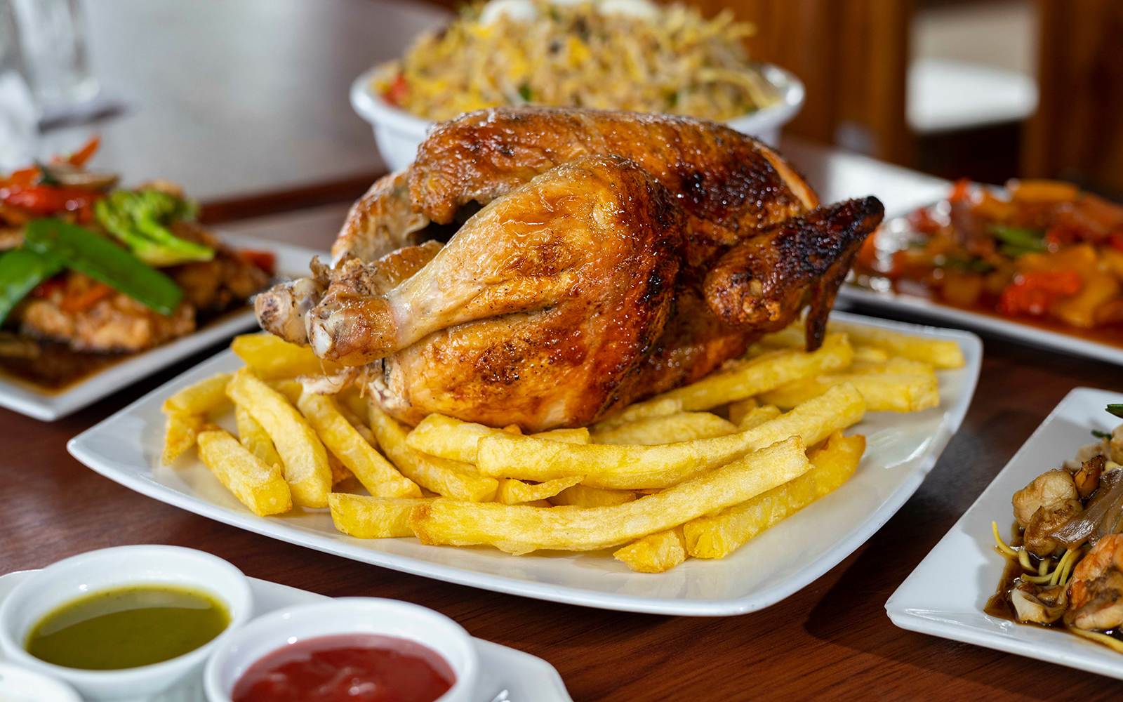 Roast chicken with fries at a restaurant, accompanied by various side dishes.