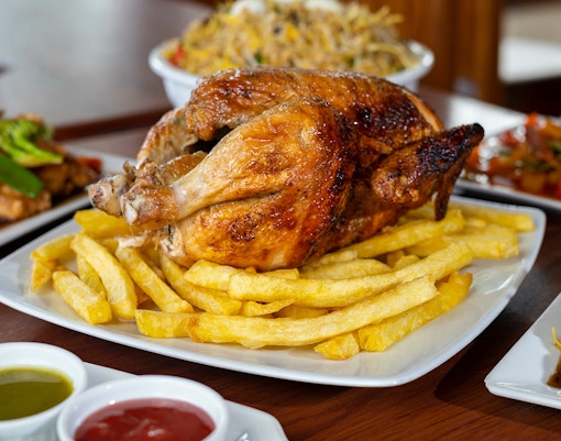 Roast chicken with fries at a restaurant, accompanied by various side dishes.