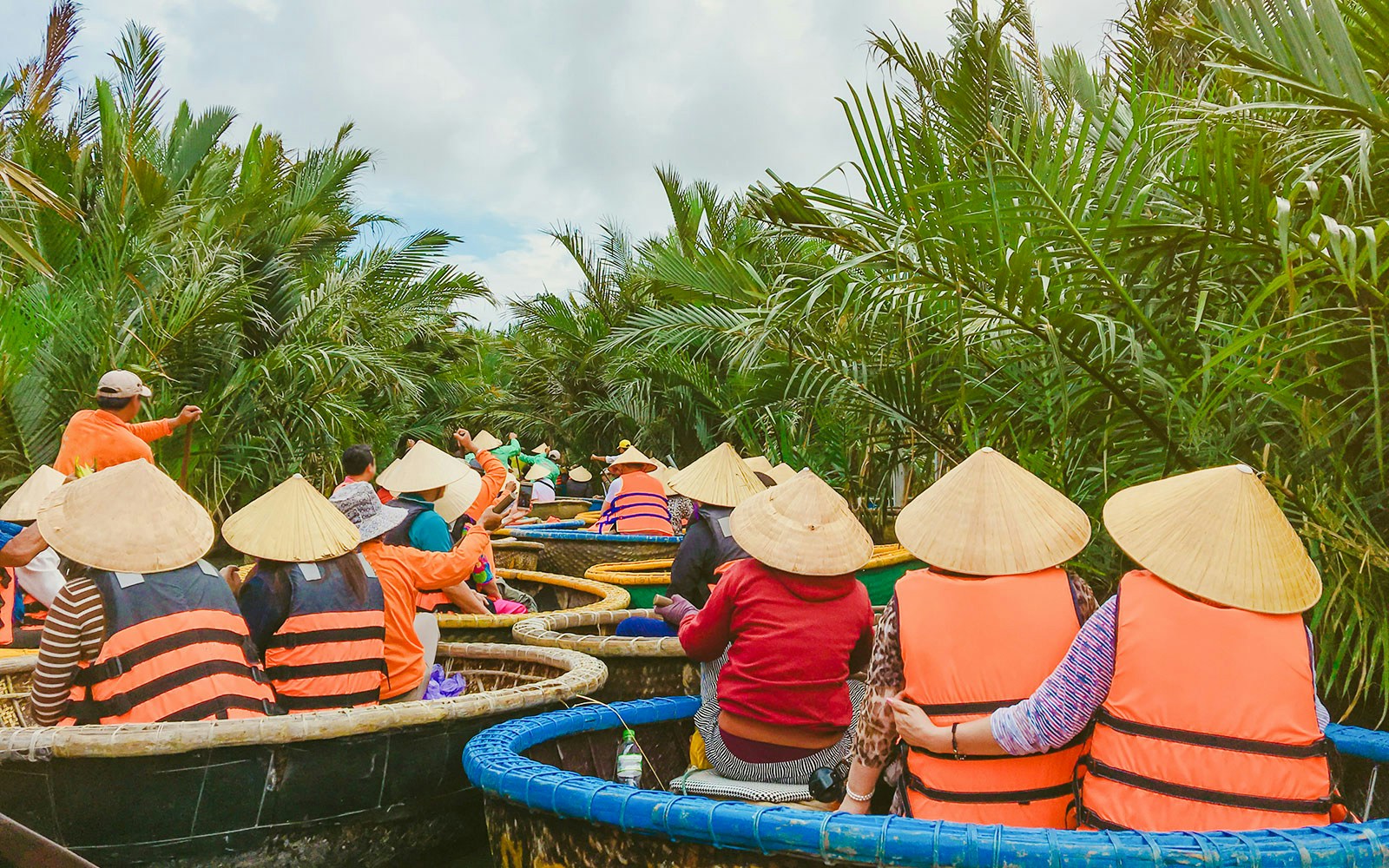 Tourists in bamboo basket boats navigating palm-lined waters in Hoi An, Vietnam.