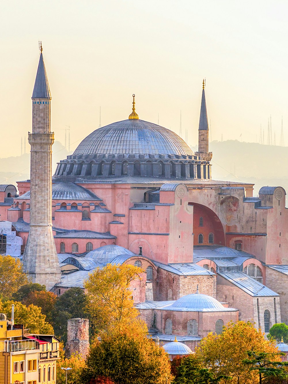 Hagia Sophia in Istanbul with minarets and domed roof surrounded by autumn trees.