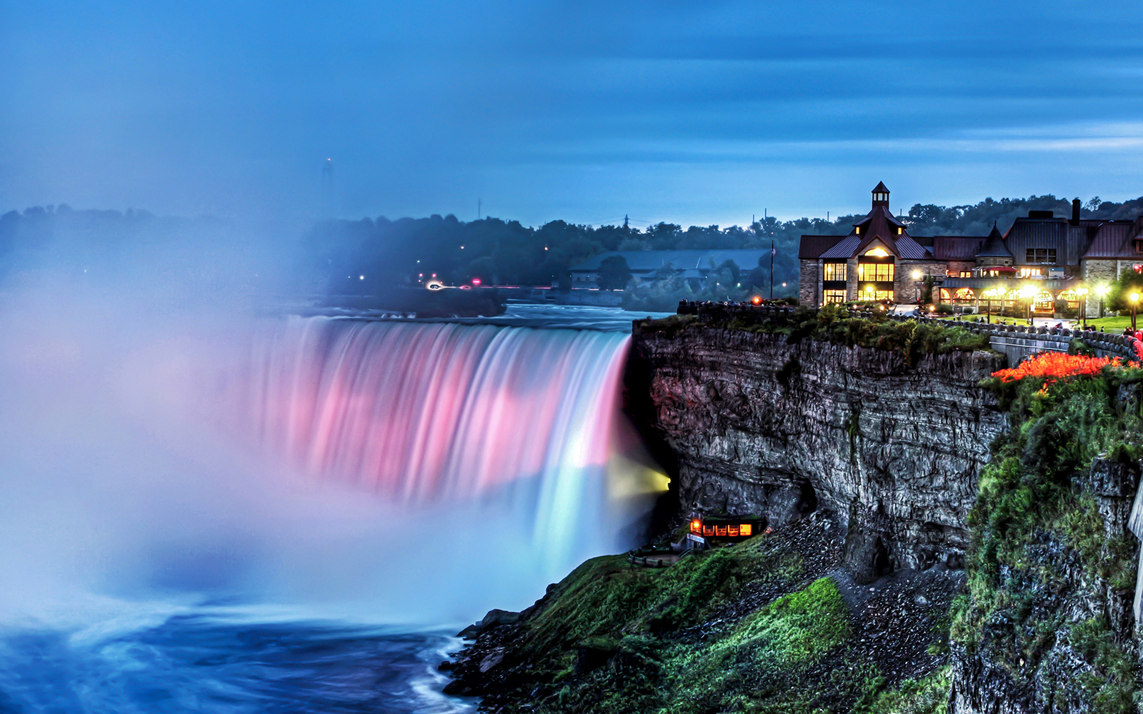 Niagara Falls illuminated at night with nearby buildings, part of Night on Niagara Walking Tour.