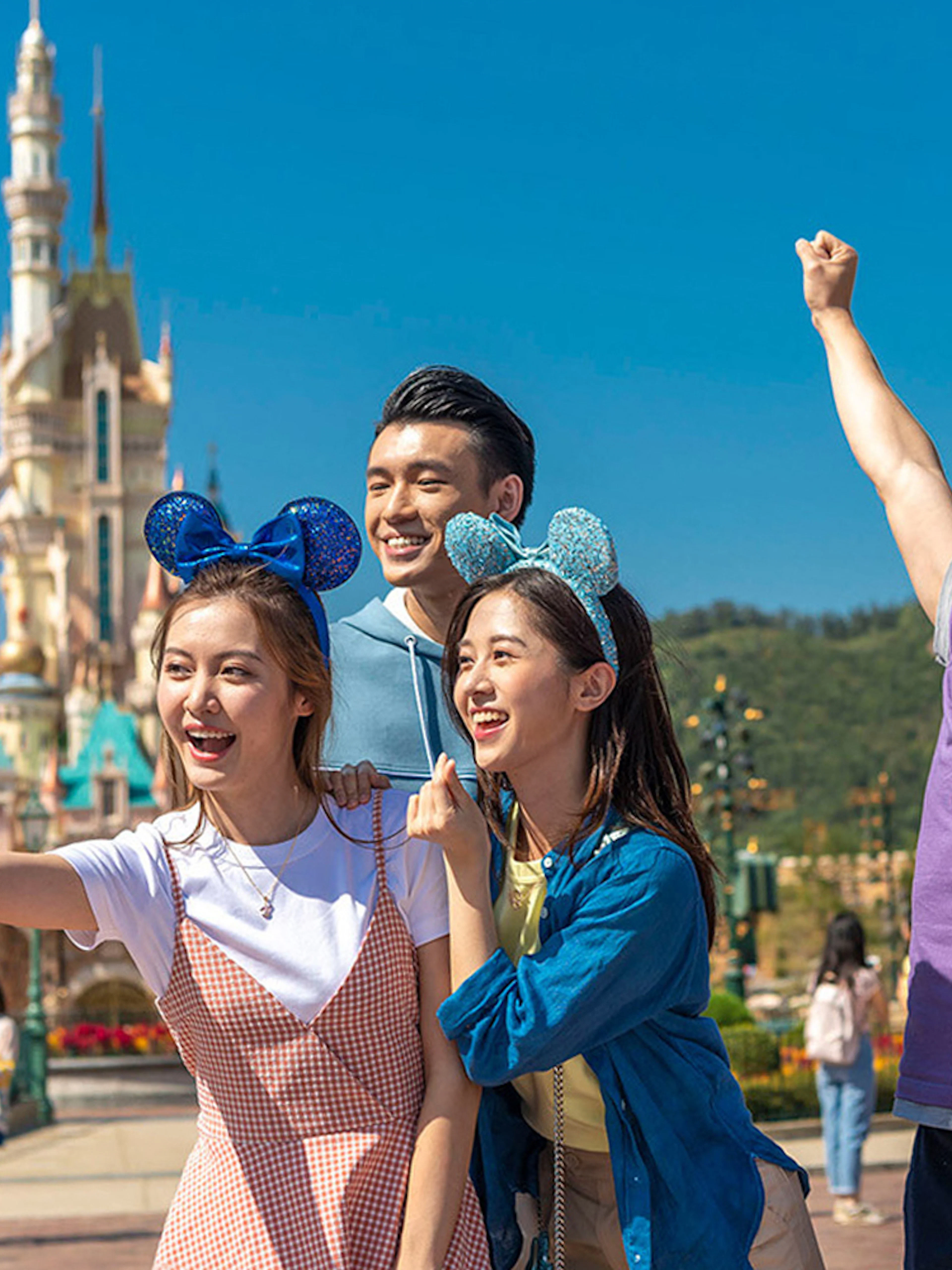 Visitors enjoying Hong Kong Disneyland with castle in background.