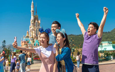 Visitors enjoying Hong Kong Disneyland with castle in background.
