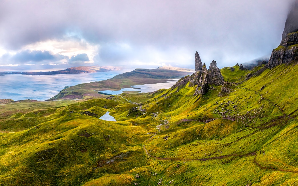 Scottish Highlands with rugged green hills and rock formations near a serene lake.