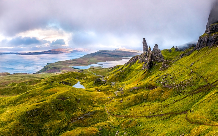 Scottish Highlands with rugged green hills and rock formations near a serene lake.