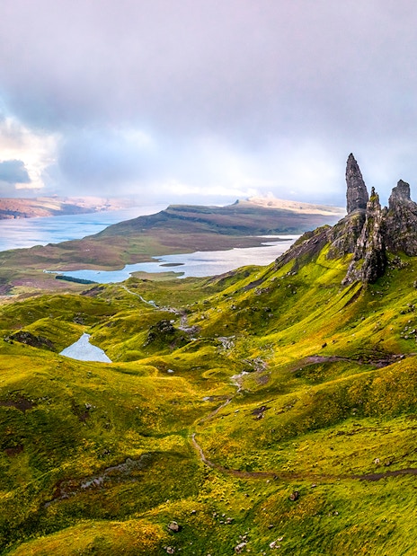 Scottish Highlands with rugged green hills and rock formations near a serene lake.