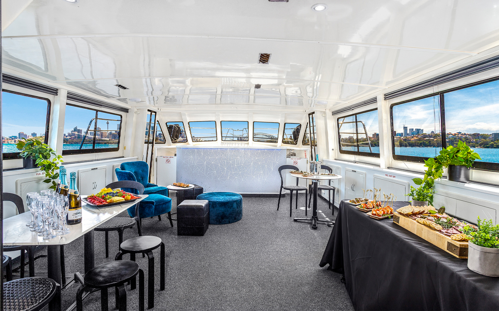 Interior of a Sydney cruise with canapés and drinks, featuring city views through large windows.