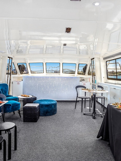 Interior of a Sydney cruise with canapés and drinks, featuring city views through large windows.
