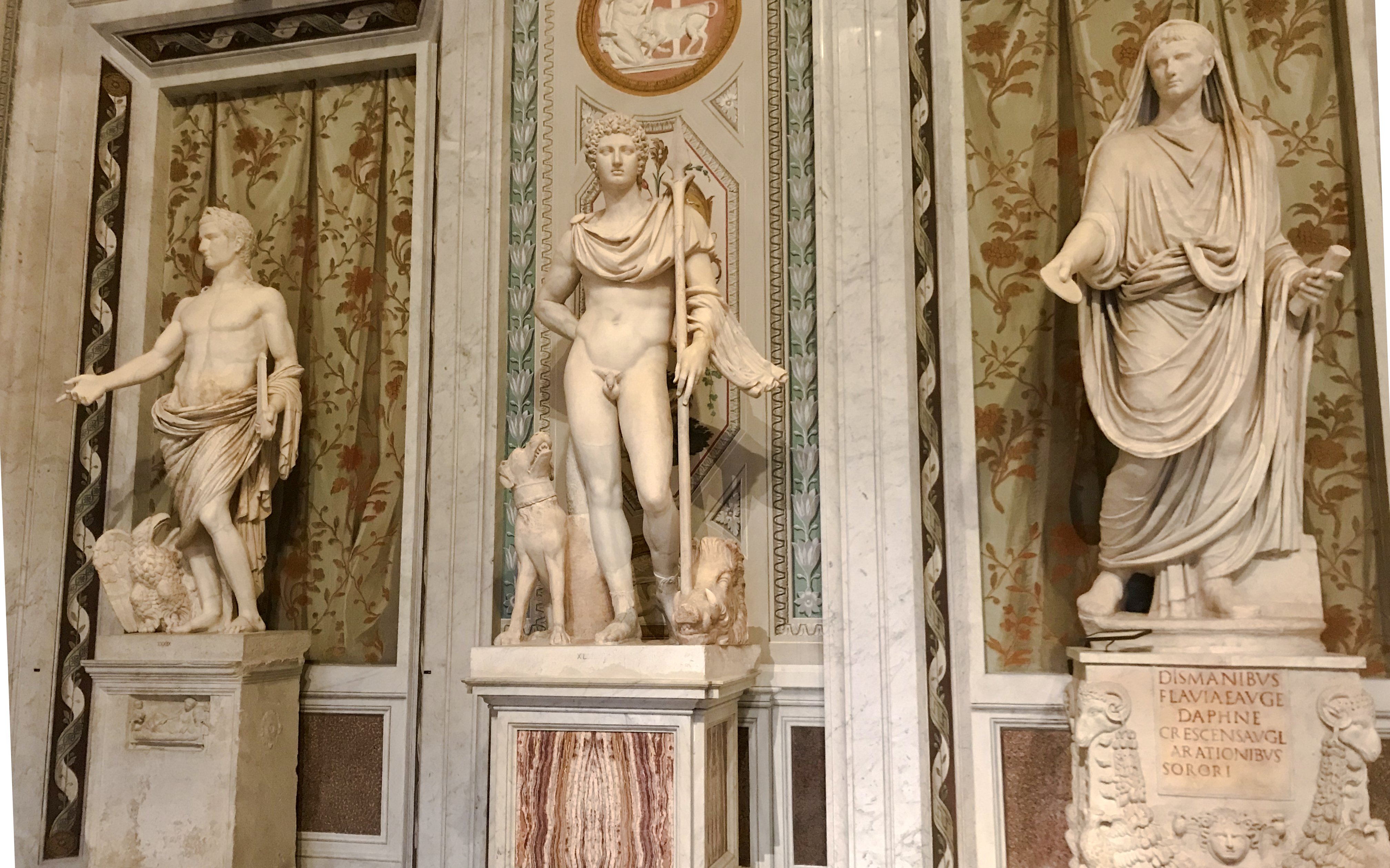 Marble statues in Borghese Gallery, Rome, depicting classical figures with intricate backgrounds.