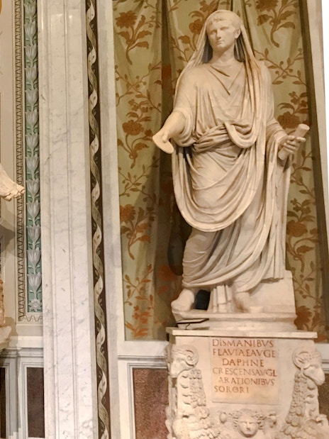 Marble statues in Borghese Gallery, Rome, depicting classical figures with intricate backgrounds.