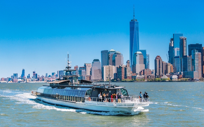 Cruise boat on Hudson River with New York City skyline in background.