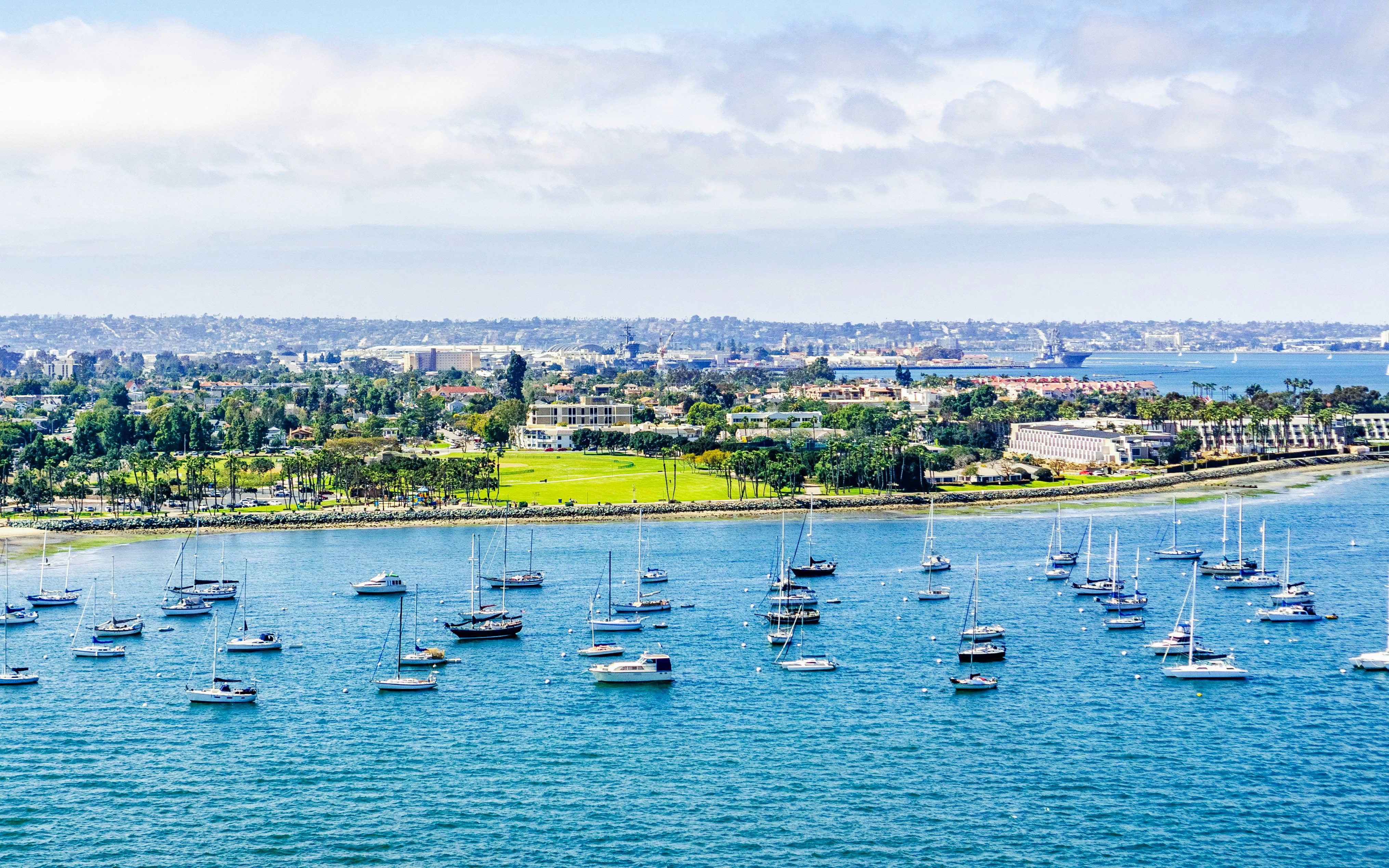 Sailboats anchored near Coronado Island, San Diego with cityscape in the background.