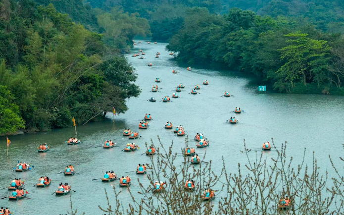 Visitors rowing boats on a river at Trang An Landscape Complex, Vietnam.
