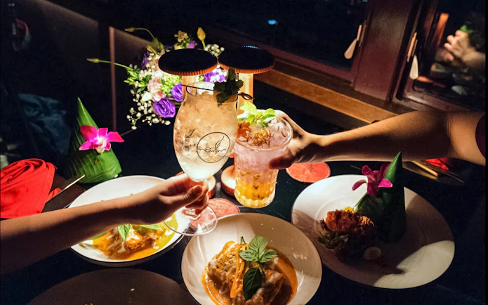 Dining experience on Saffron Luxury Cruise by Banyan Tree with cocktails and gourmet dishes.
