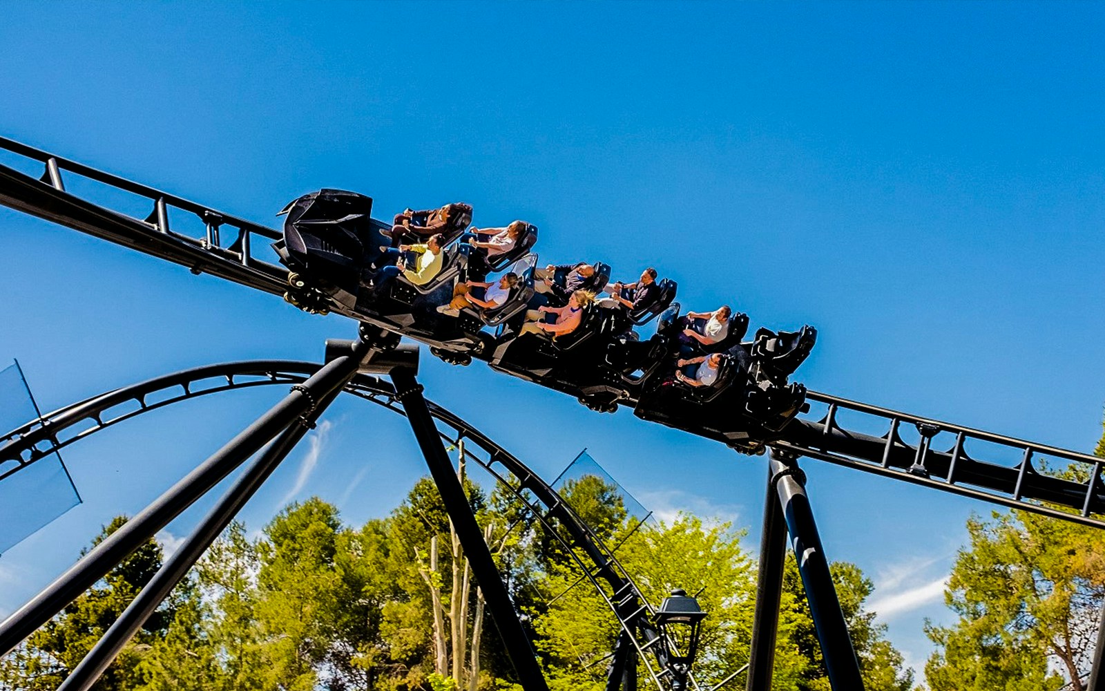 Parque Warner Madrid roller coaster with Warner Bros characters and visitors enjoying the ride.