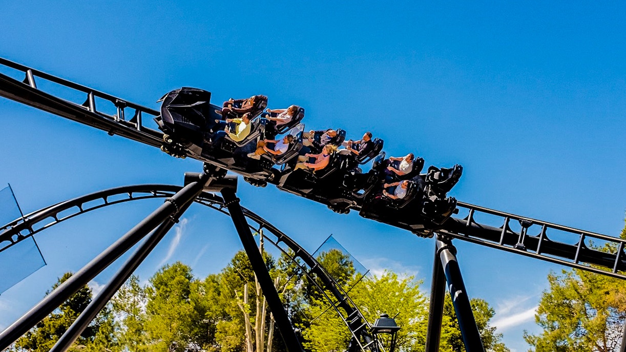 Parque Warner Madrid roller coaster with Warner Bros characters and visitors enjoying the ride.