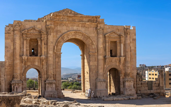 The Arch of Hadrian in Jerash, Jordan, with surrounding ancient ruins.