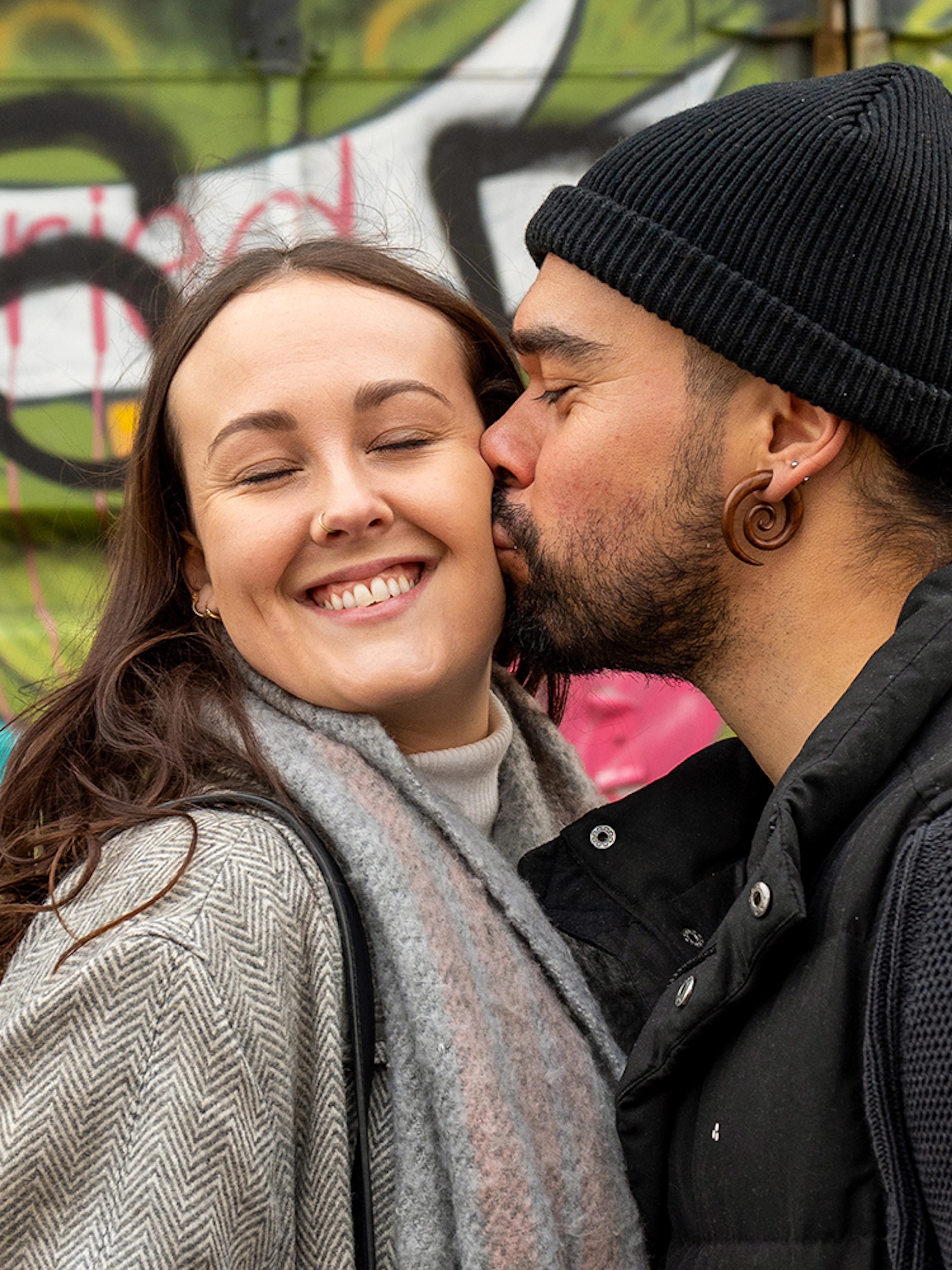 Couple posing in front of colorful graffiti at NDSM, Amsterdam.