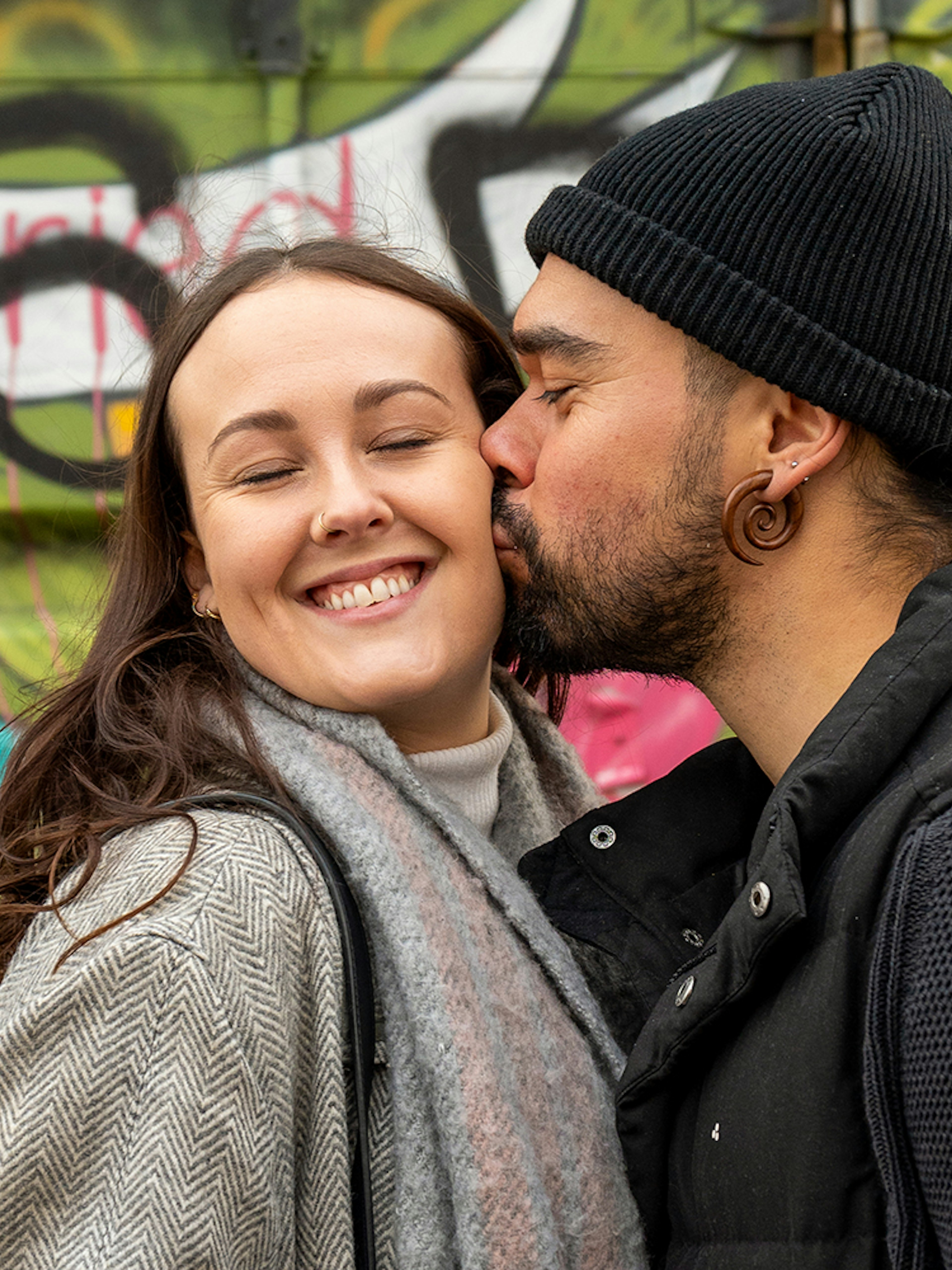 Couple posing in front of colorful graffiti at NDSM, Amsterdam.