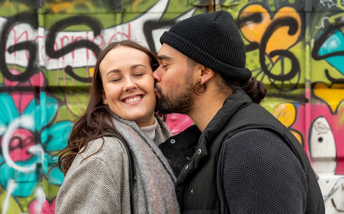 Couple posing in front of colorful graffiti at NDSM, Amsterdam.