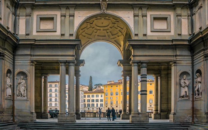 Uffizi Gallery entrance with statues and view of Florence buildings.