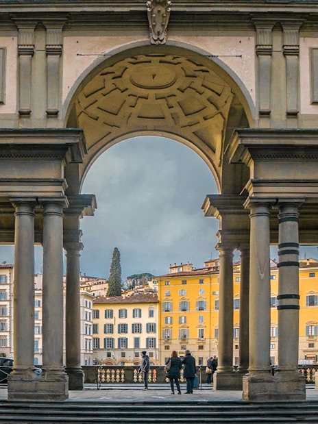 Uffizi Gallery entrance with statues and view of Florence buildings.