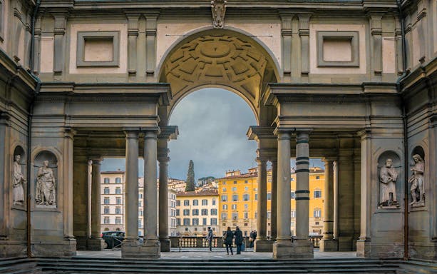Uffizi Gallery entrance with statues and view of Florence buildings.