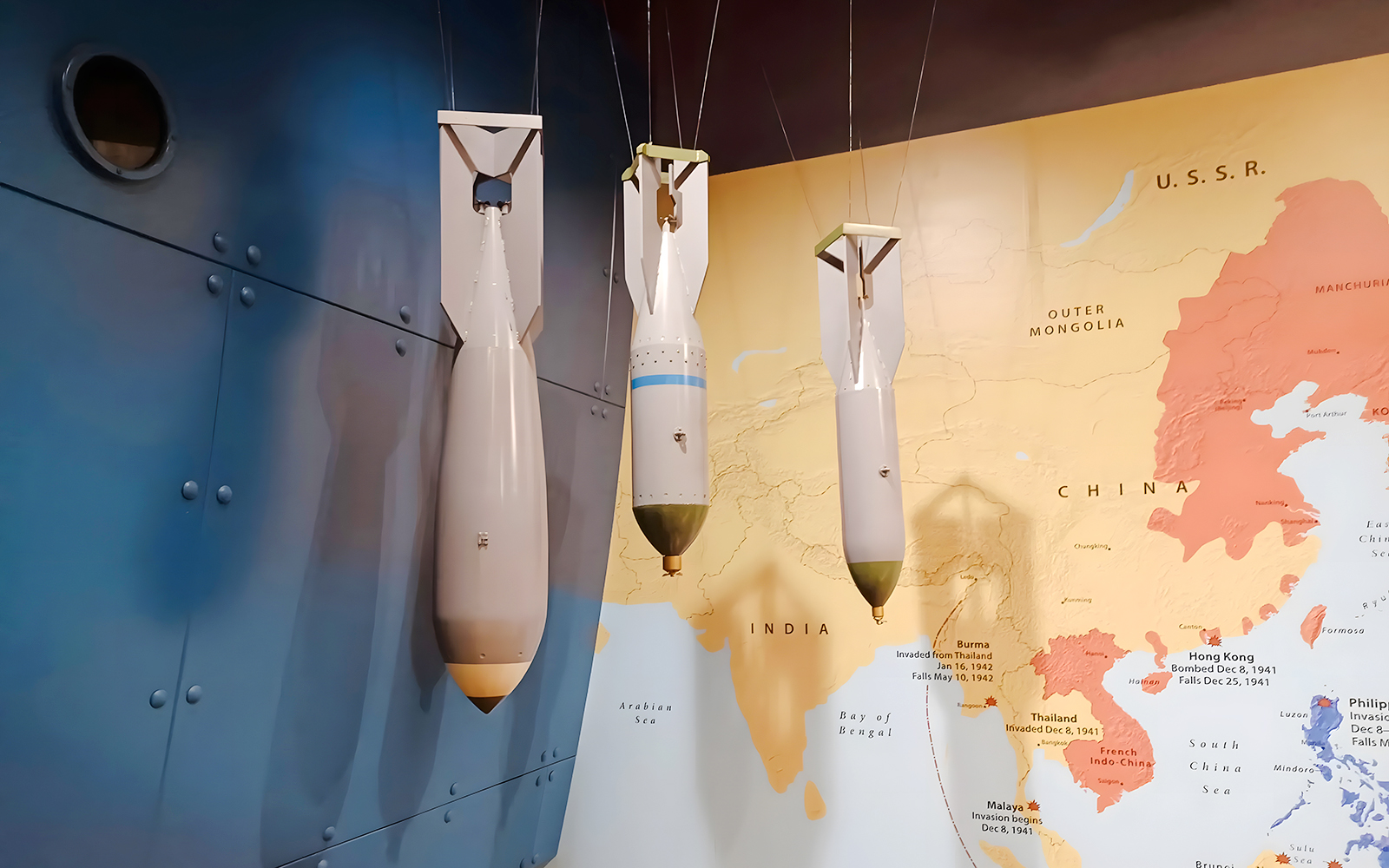 World War II bombs displayed against a map backdrop at USS Arizona tour exhibit.