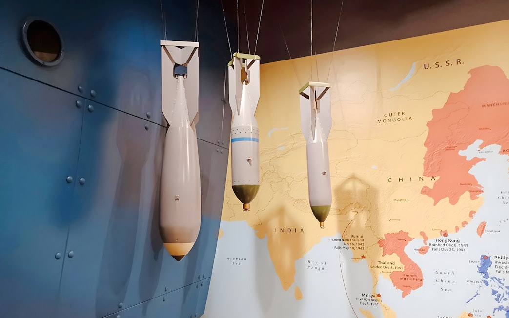 World War II bombs displayed against a map backdrop at USS Arizona tour exhibit.