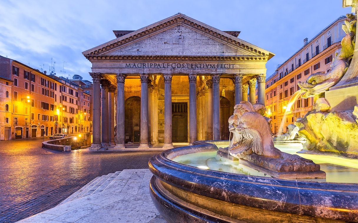 Pantheon in Rome with illuminated fountain at sunset.