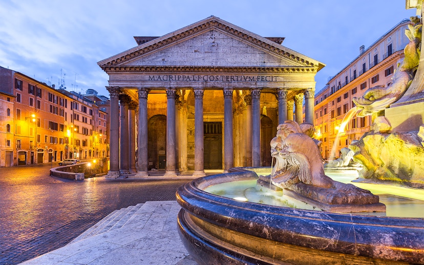 Pantheon in Rome with illuminated fountain at sunset.